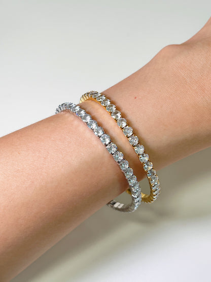Detailed side profile view of 18K gold PVD and silver tone 4mm elastic tennis bracelets on an arm demonstrating the flexible setting.