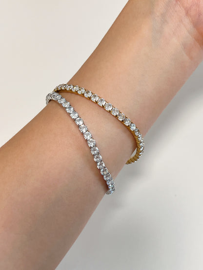 Pair of gold and silver 4mm elastic diamond tennis bracelets stacked together on a wrist showcasing the continuous gemstone layout.