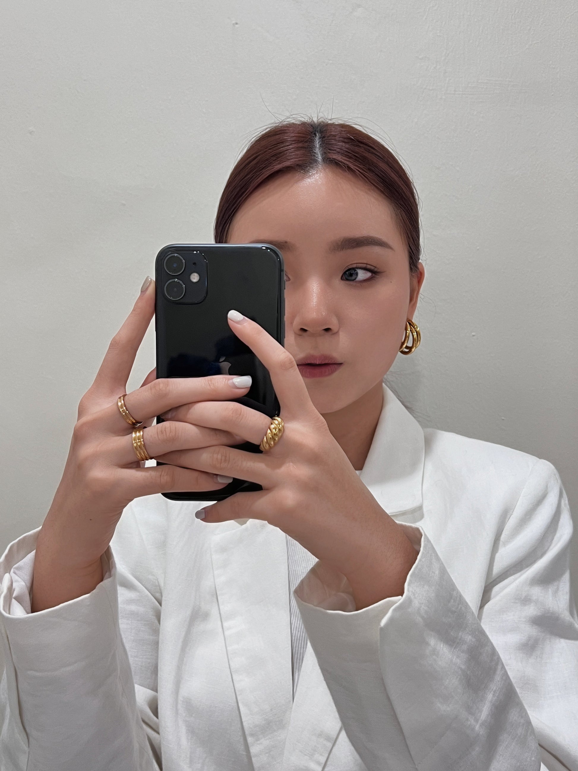Lifestyle selfie shot of thick gold ridged ring and ribbed rings with white outfit