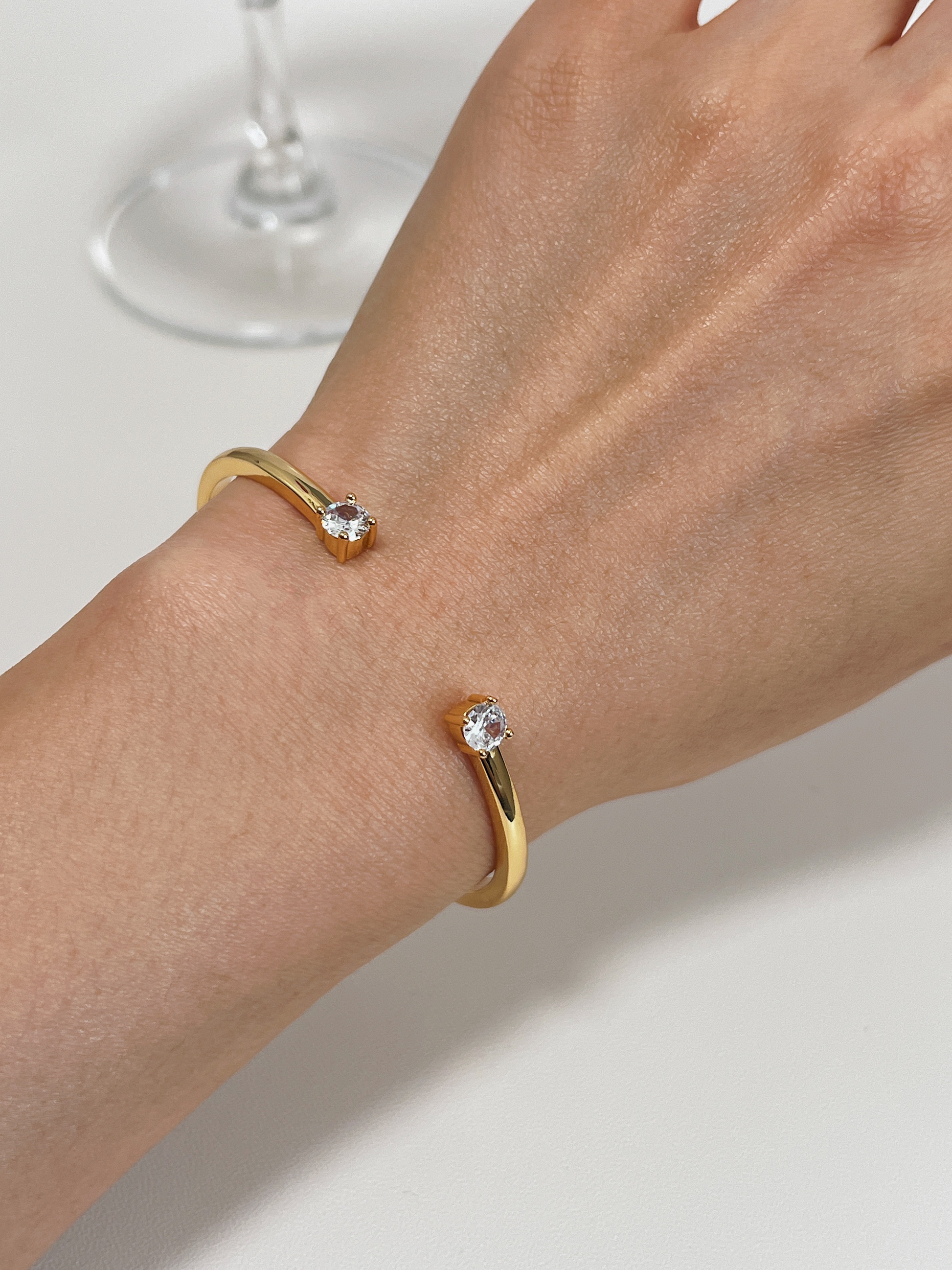 An elegant close-up of a model's arm wearing the gold Justine adjustable double-crystal cuff.