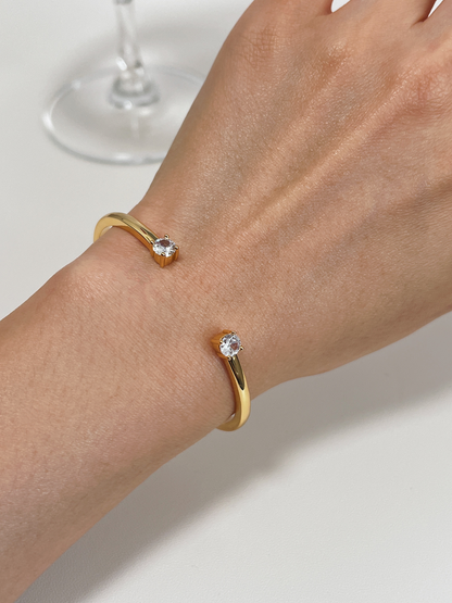 An elegant close-up of a model's arm wearing the gold Justine adjustable double-crystal cuff.