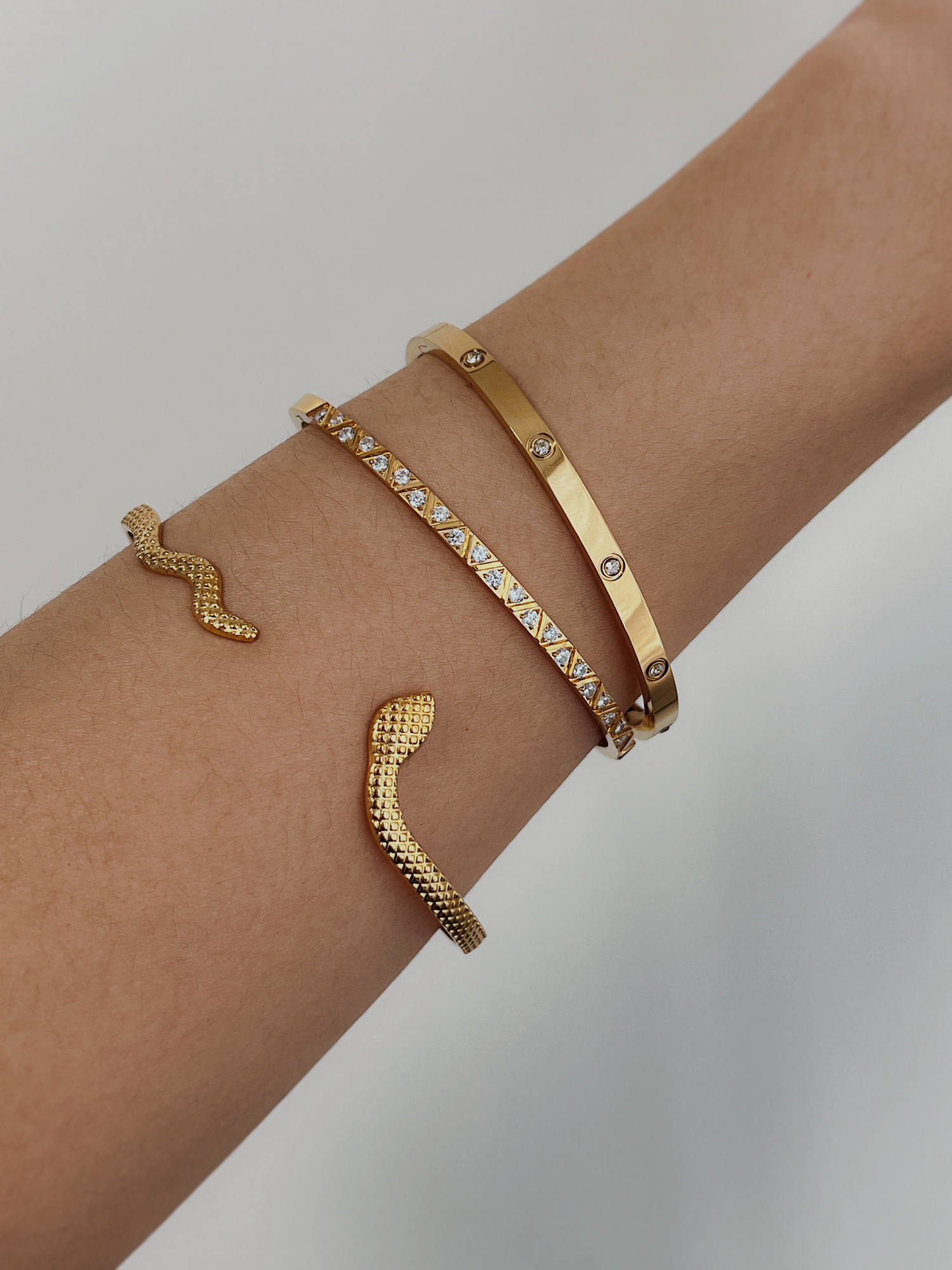 Elegant model wrist shot wearing the complete trio of gold bangles for an upscale daytime look.