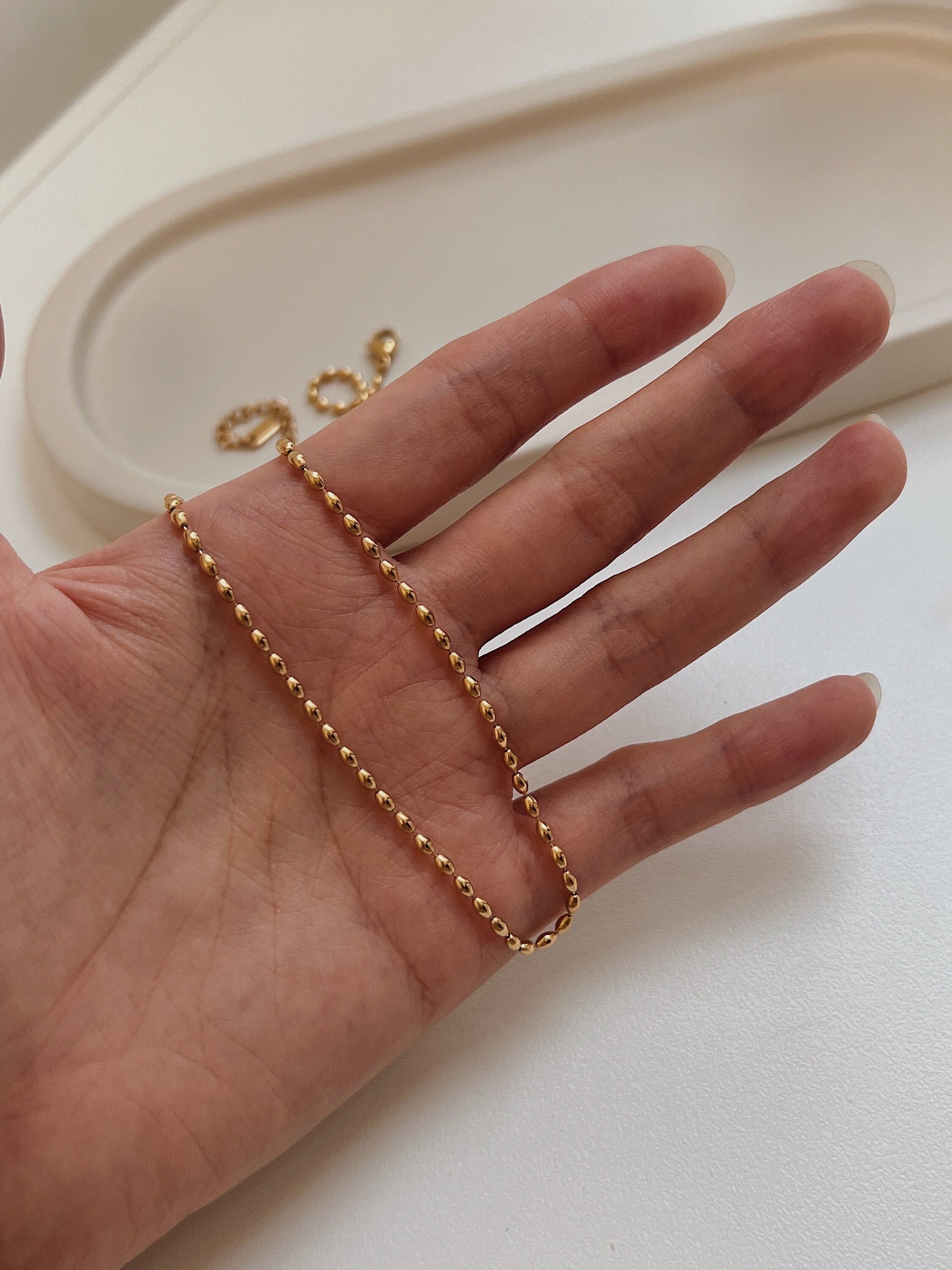 Studio view of the Livia beaded choker necklace resting gracefully across an open palm showcasing its fluid movement