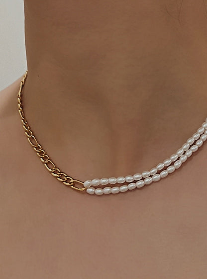 Model view wearing an asymmetrical figaro chain and double row seed pearl necklace