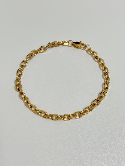 Flatlay view focusing on the uniform, interlocking oval architecture and polished metallic finish of the gold cable chain bracelet.