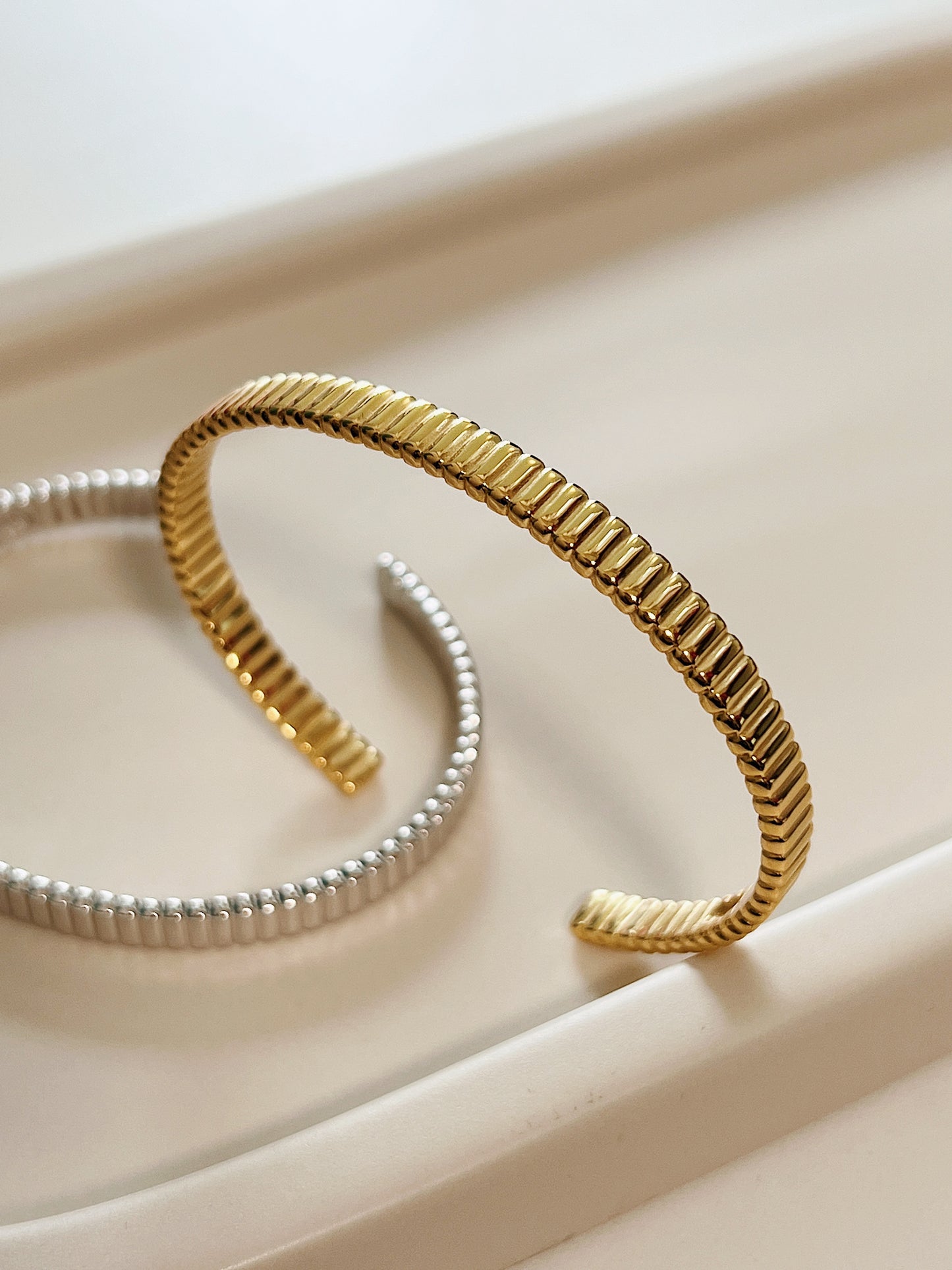 High-resolution product shot capturing the flexible opening profile of the gold vermeil flexi cuff bangle with silver at the back.