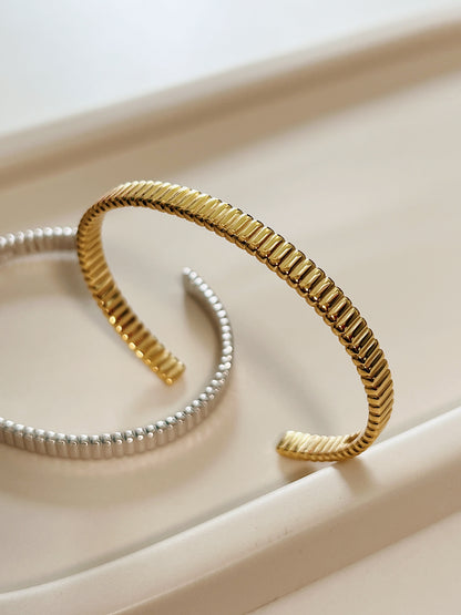 High-resolution product shot capturing the flexible opening profile of the gold vermeil flexi cuff bangle with silver at the back.