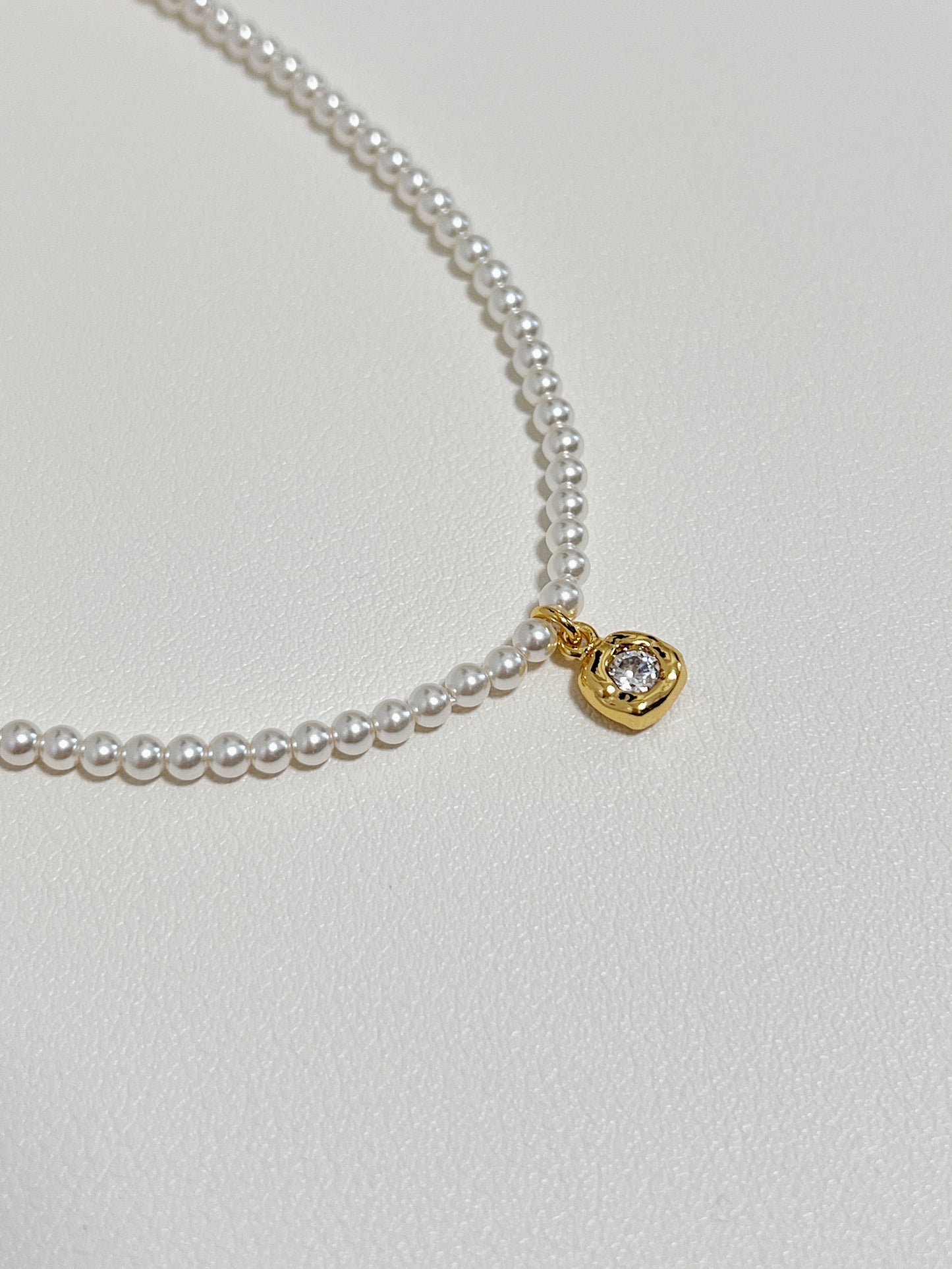 Macro jewelry photography capturing light refracting through a brilliant-cut cubic zirconia charm inside a molten bezel frame