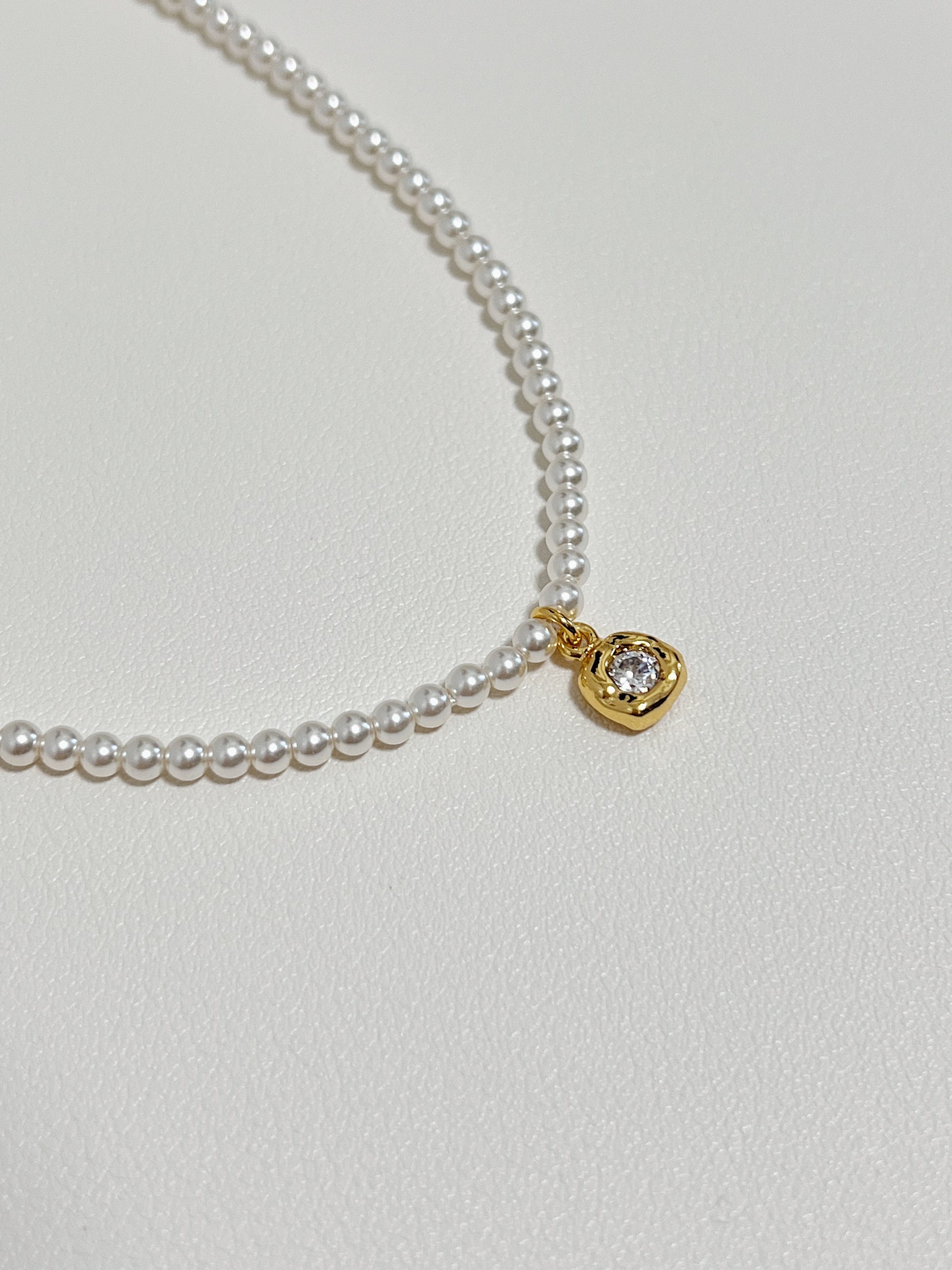 Macro jewelry photography capturing light refracting through a brilliant-cut cubic zirconia charm inside a molten bezel frame