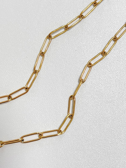 Macro jewelry photography capturing light reflecting off the smooth beveled edges of an 18k gold PVD rectangular link chain