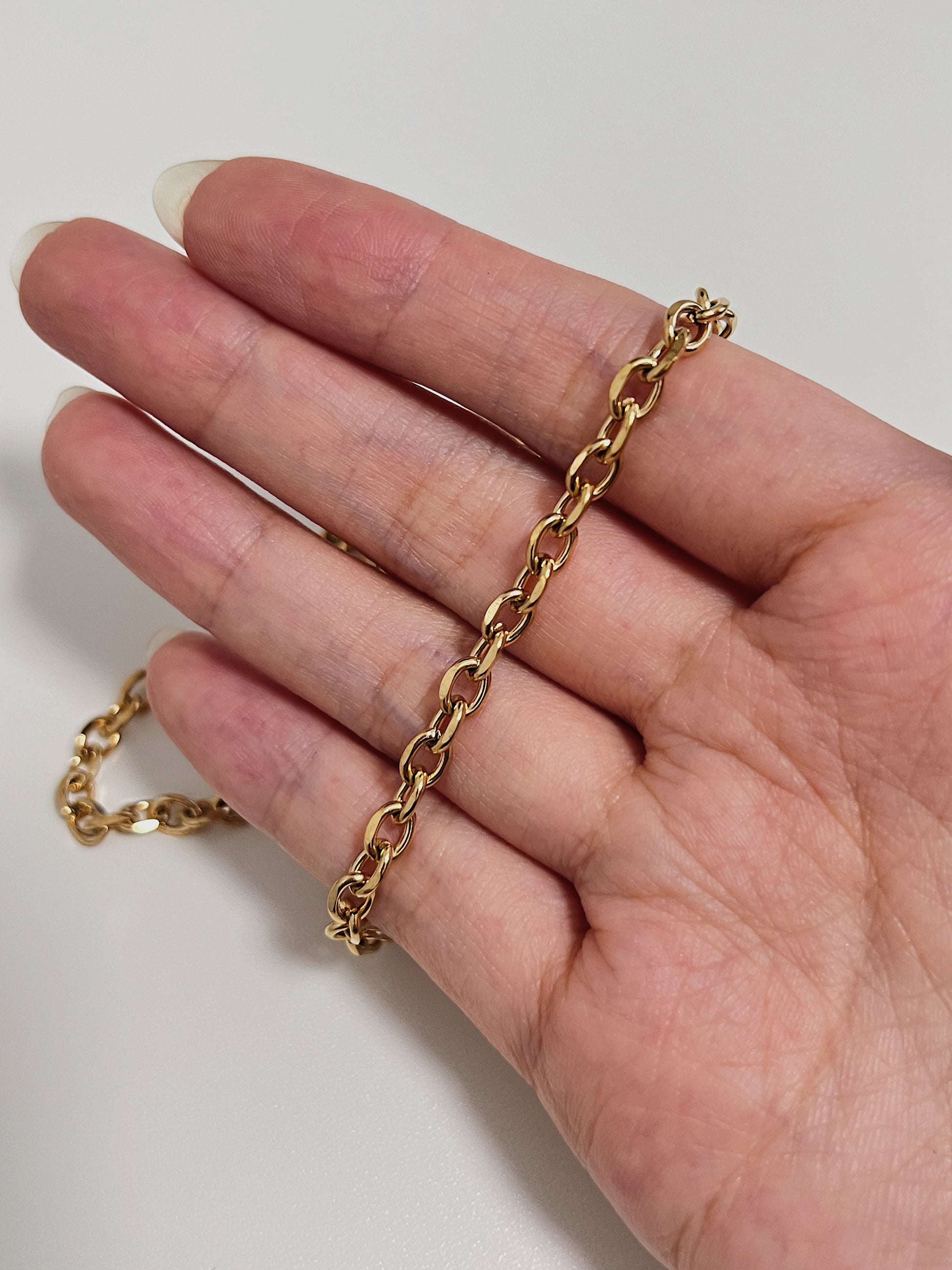 Aurous atelier studio presentation illustrating a heavy gold cable chain resting on hand
