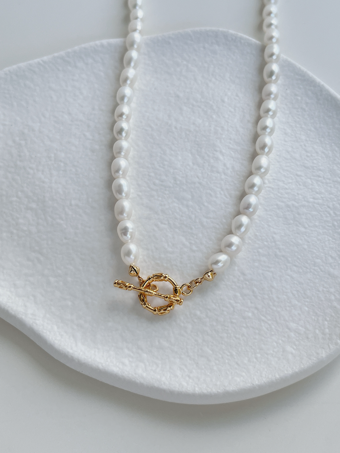 Madeleine freshwater pearl strand necklace displaying the ornate gold toggle clasp front centerpiece