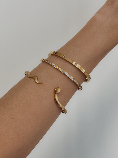 A model styling the textured Margot gold serpent cuff bracelet layered with the polished Dane six-stone gemstone bangle and gia geometric bangle. 