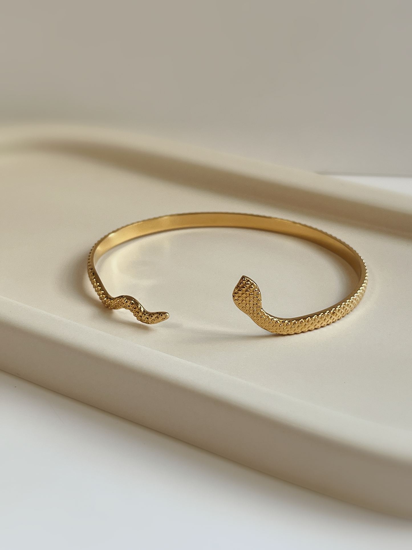 Close-up profile of the Margot gold serpent cuff bracelet, highlighting the detailed scale-like metallic texture and open bypass design.