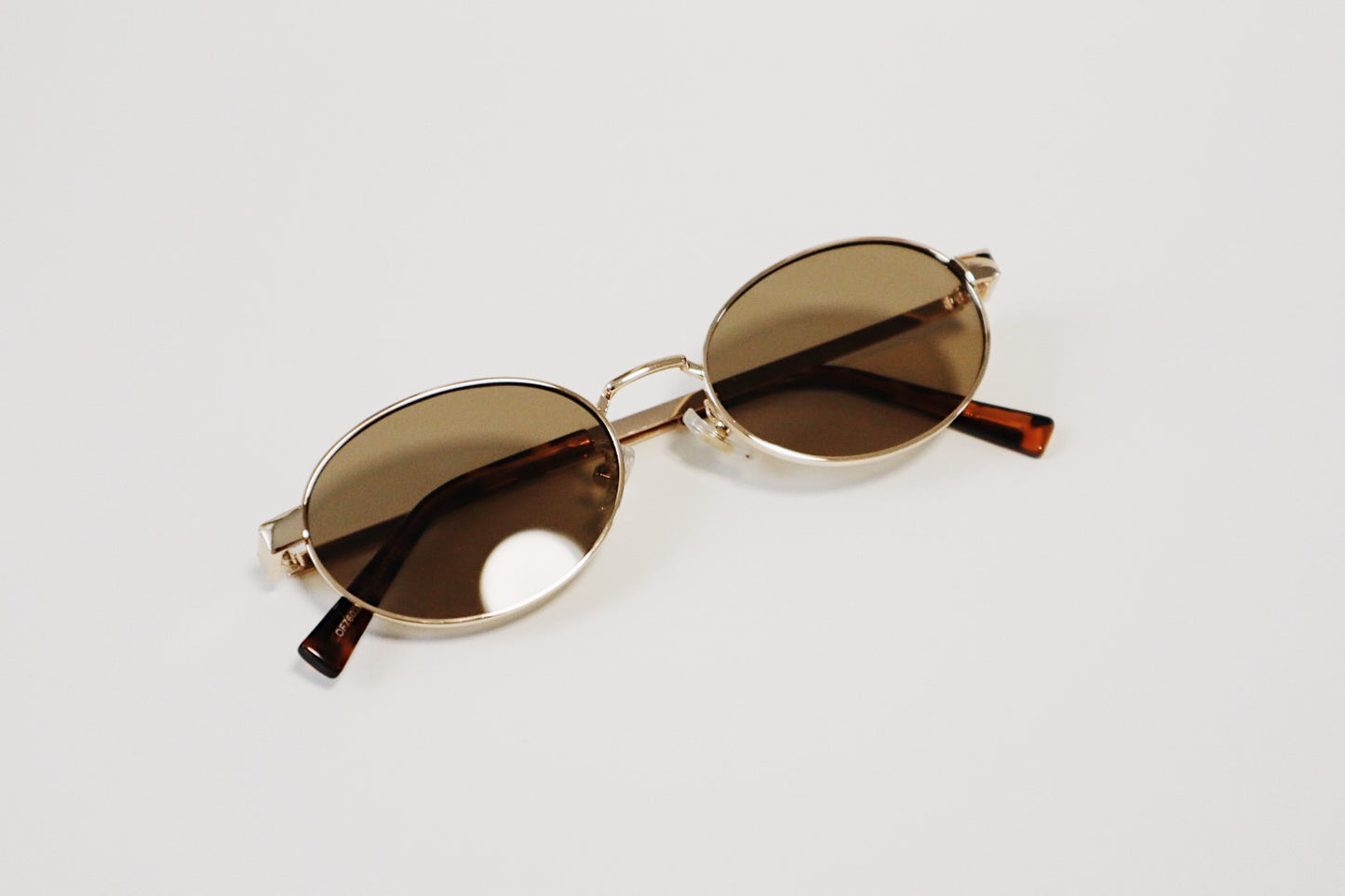 The Marseille sunglasses folded neatly on an organic tray, highlighting the lightweight, low-profile arm structure and minimalist design.
