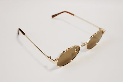 Overhead flatlay of Marseille gold sunglasses neatly placed on a white surface