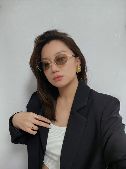 Selfie mid-shot of a model wearing Marseille amber-tinted sunglasses with a tailored blazer for a chic city style.