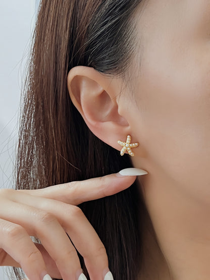 Model ear shot showing the gold pearl starfish clip-on earring resting flush against the lobe for a seamless pierced look.