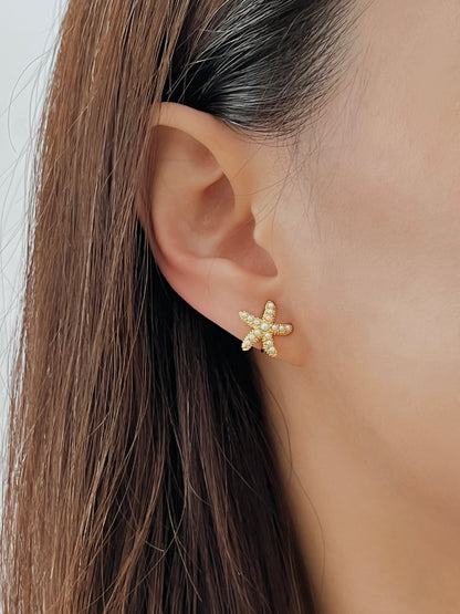 Close-up ear shot of model wearing the pearl starfish clip-on catching warm golden hour sunlight.