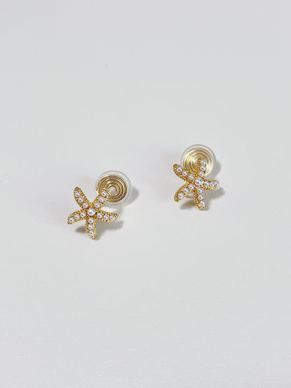 Studio flatlay display showcasing the compact 13mm starfish shape and delicate pearl detailing of the clip-on earring pair.