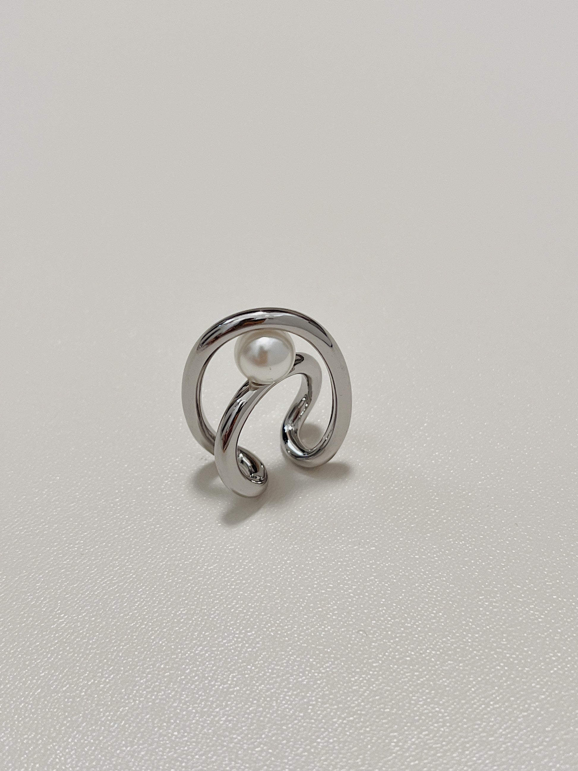Isolated product view of the silver Karolina Statement Earlobe Cuff, showing how the open, non-adjustable double loop structure cradles the floating central pearl.