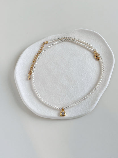 Minimalist flatlay presentation showcasing the Alta pearl pendant strand on a ceramic plate