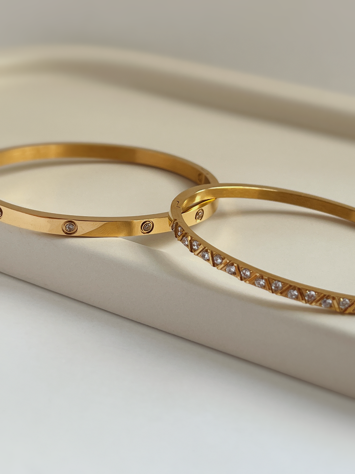 A polished stack of both gold finished stainless steel gemstone bangles showing how easily the styles nest together.