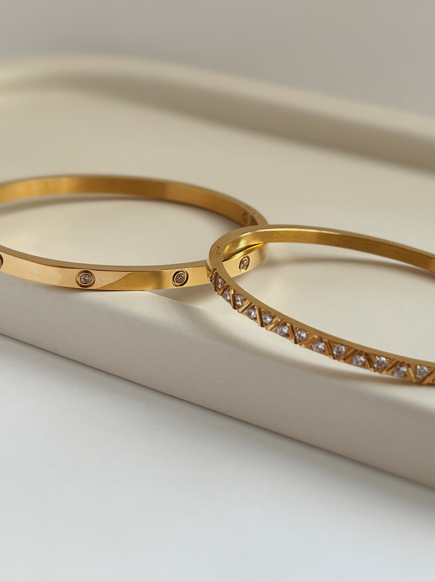 A polished stack of both gold finished stainless steel gemstone bangles showing how easily the styles nest together.