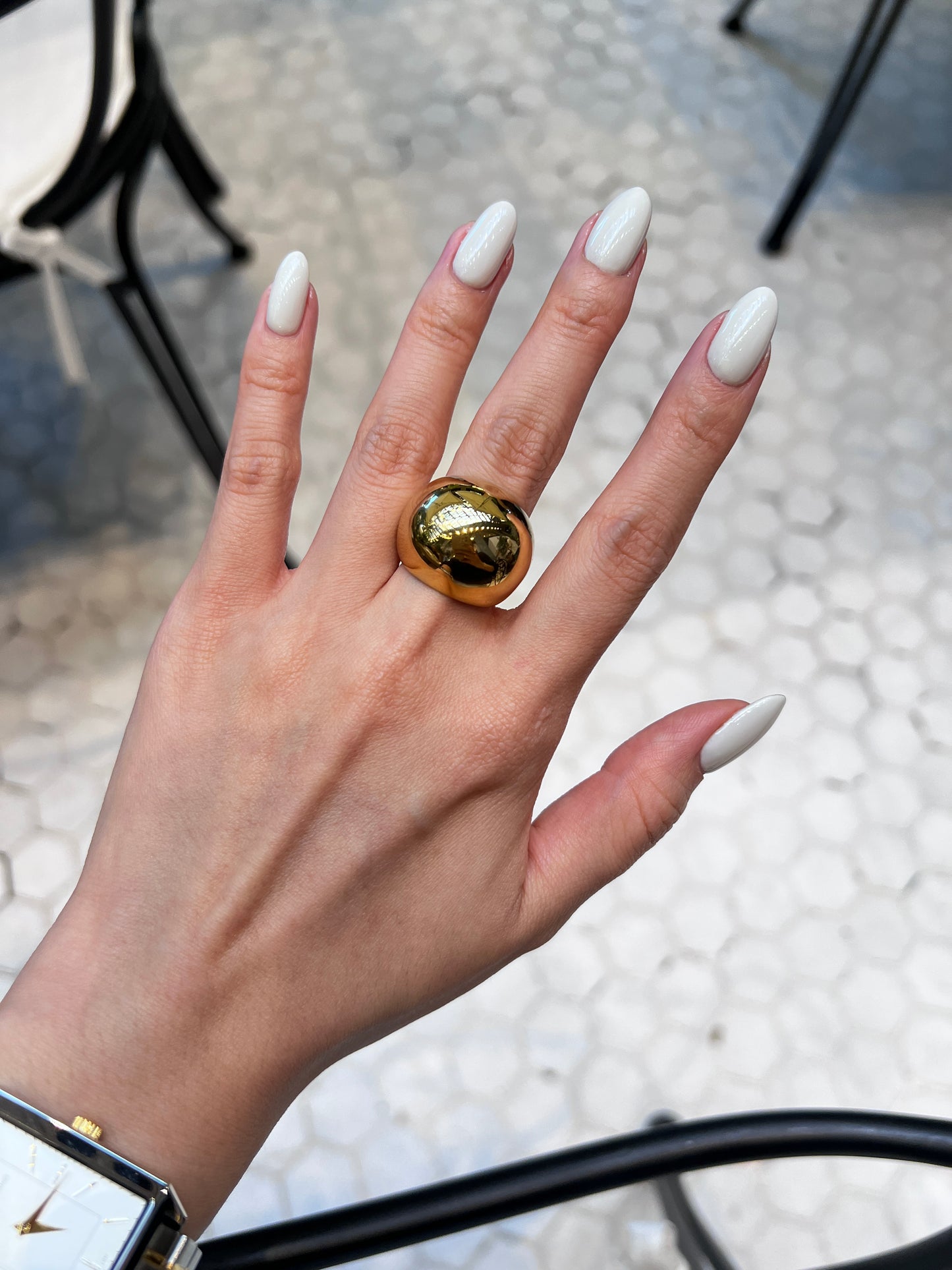 Close-up of model wearing thick gold statement band with a rectangle watch