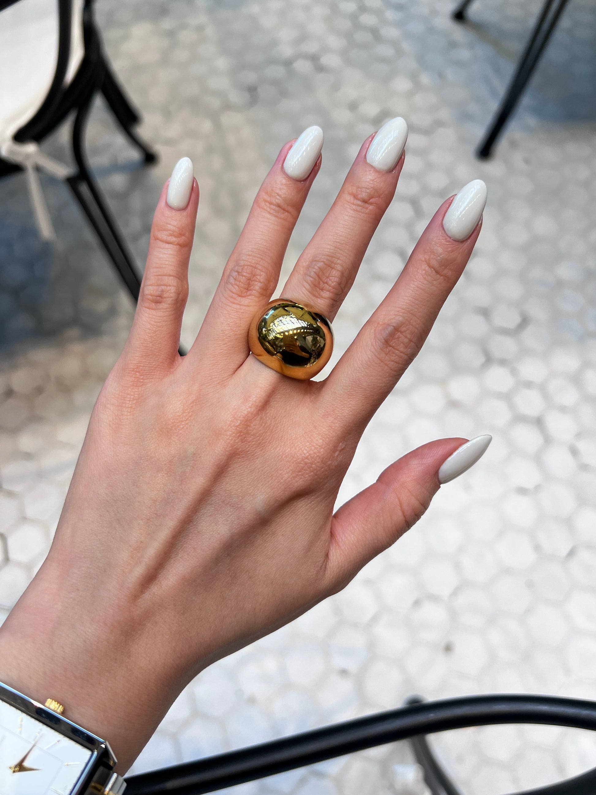 Close-up of model wearing thick gold statement band with a rectangle watch