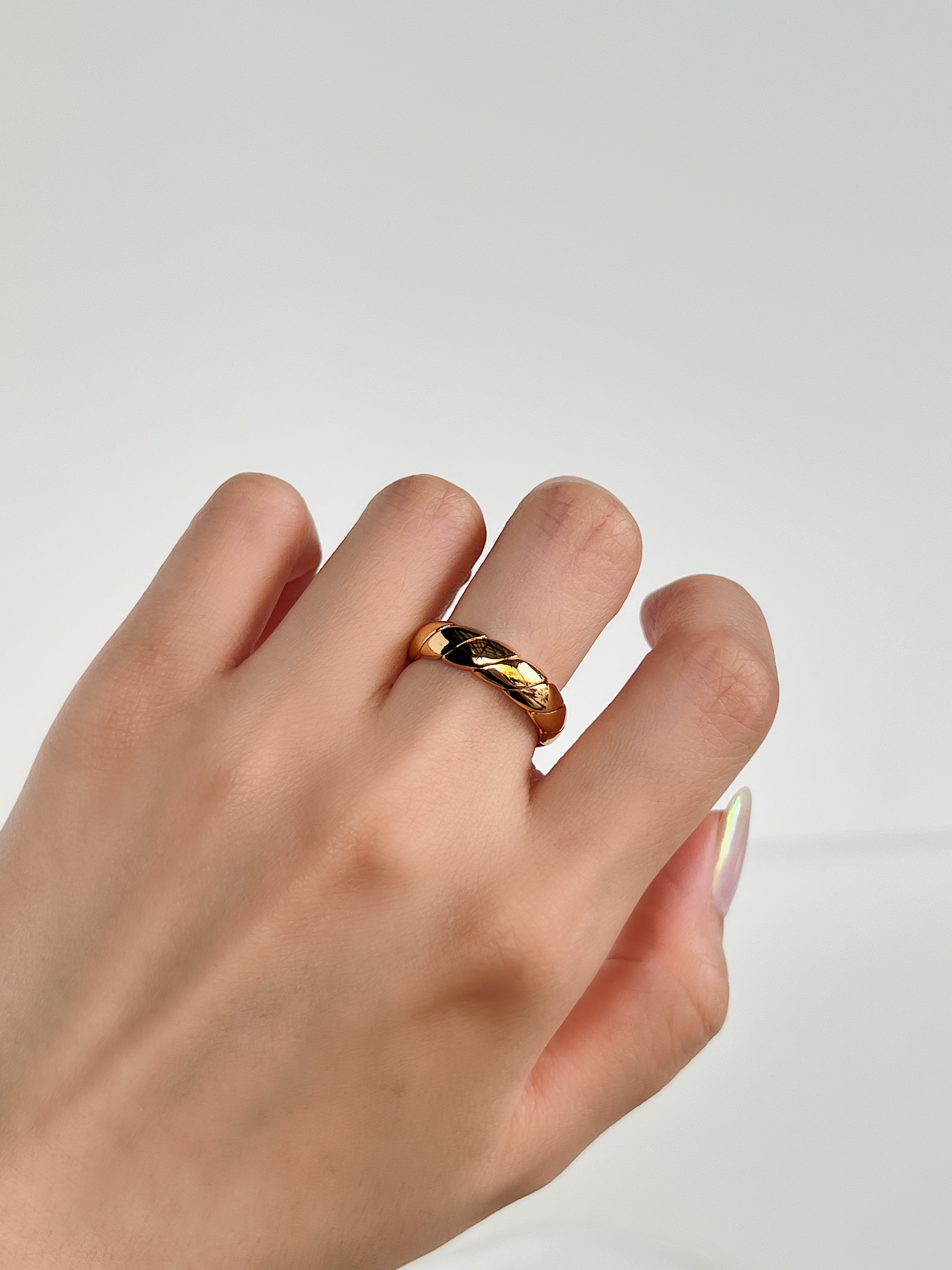 Close up view of a woman hand showing the adjustable gold twill ring styled at middle finger