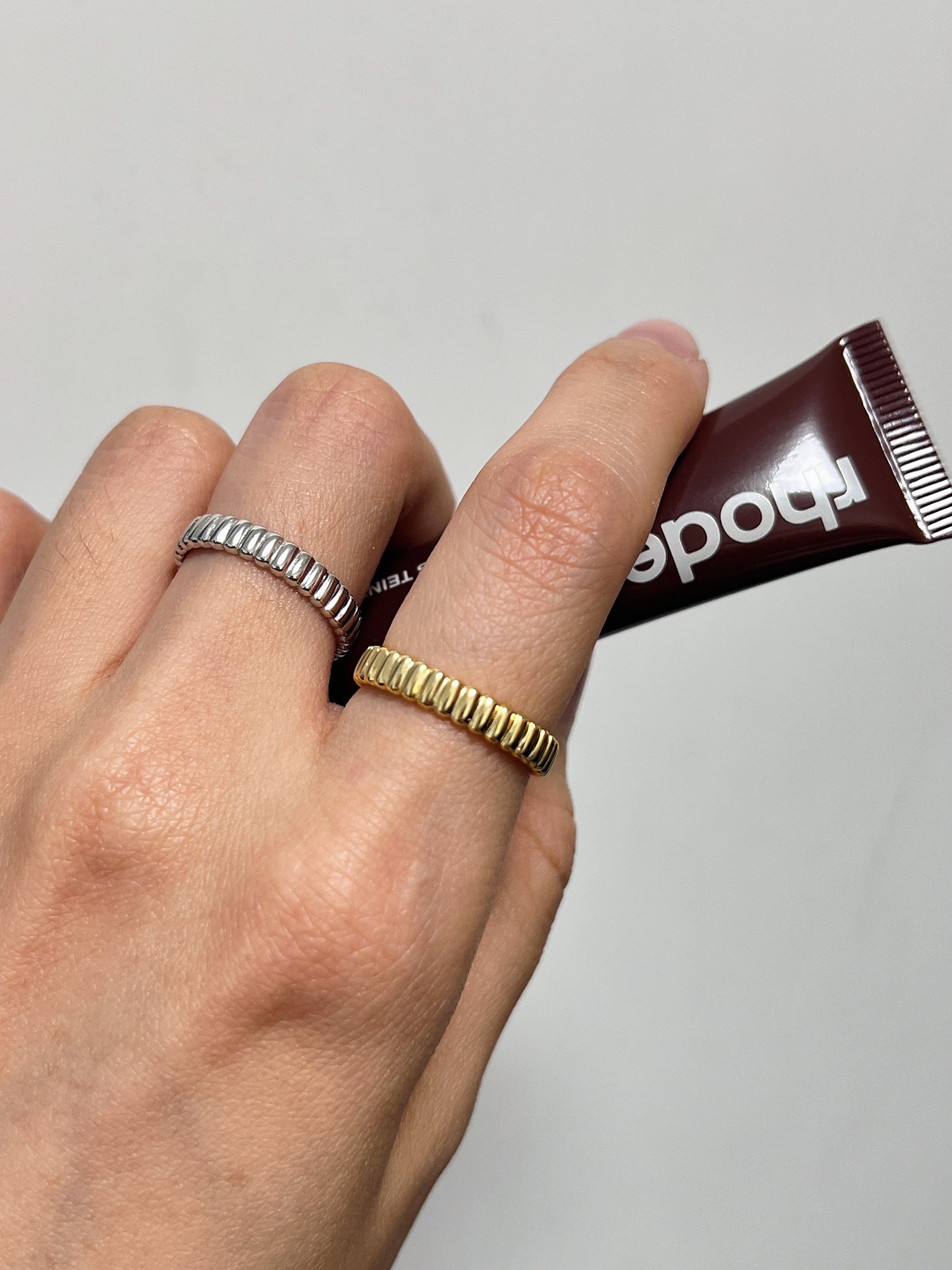 Close up of a model hand styling a set of 4mm gold and silver fluted ring with minimalist wardrobe