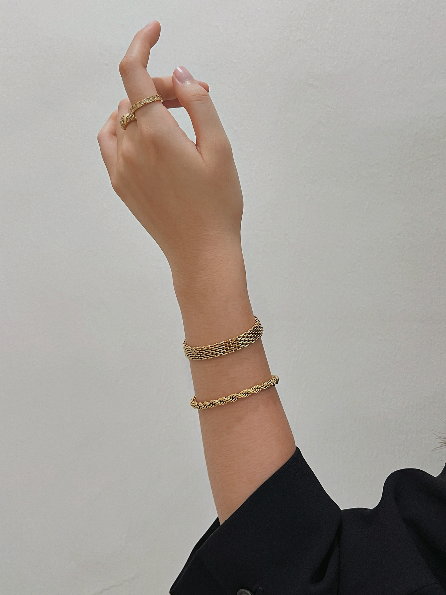 A model wearing the Cali 5mm gold twisted rope bracelet stacked with a mesh band and gold rings.