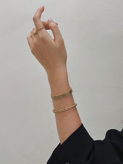 A model wearing the Cali 5mm gold twisted rope bracelet stacked with a mesh band and gold rings.
