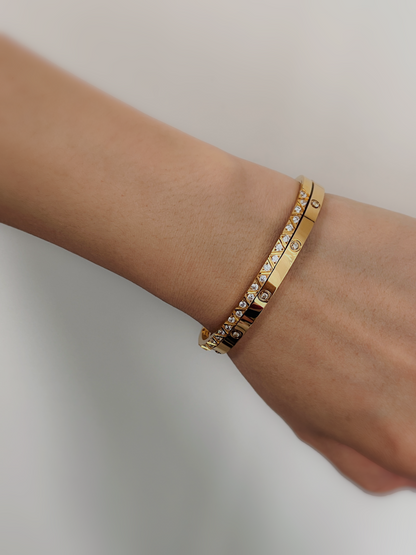 A close-up of a model's wrist wearing a stack of the Gia and Dane gold gemstone bangles, styled with a cozy neutral knit sleeve.