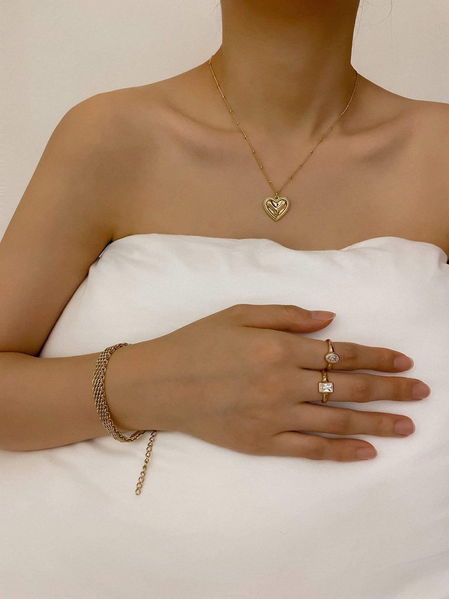 A model wearing the gold Danielle mesh chain bracelet on her wrist, paired with a delicate gold heart pendant necklace and minimal stacking rings.