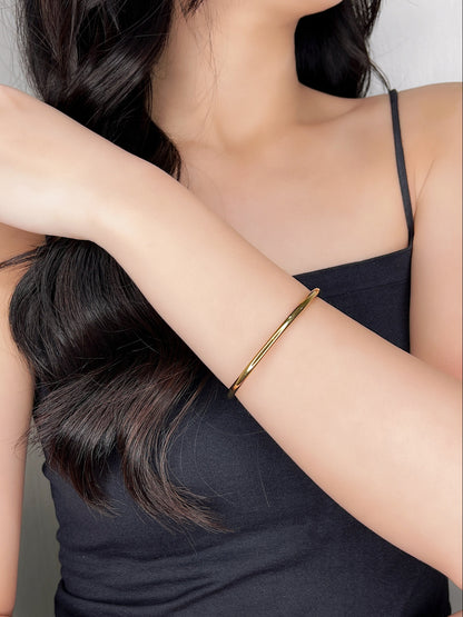Close-up profile of a model wearing the Ines minimal cuff bangle on her wrist, styled elegantly with a black tank top for a refined everyday look.