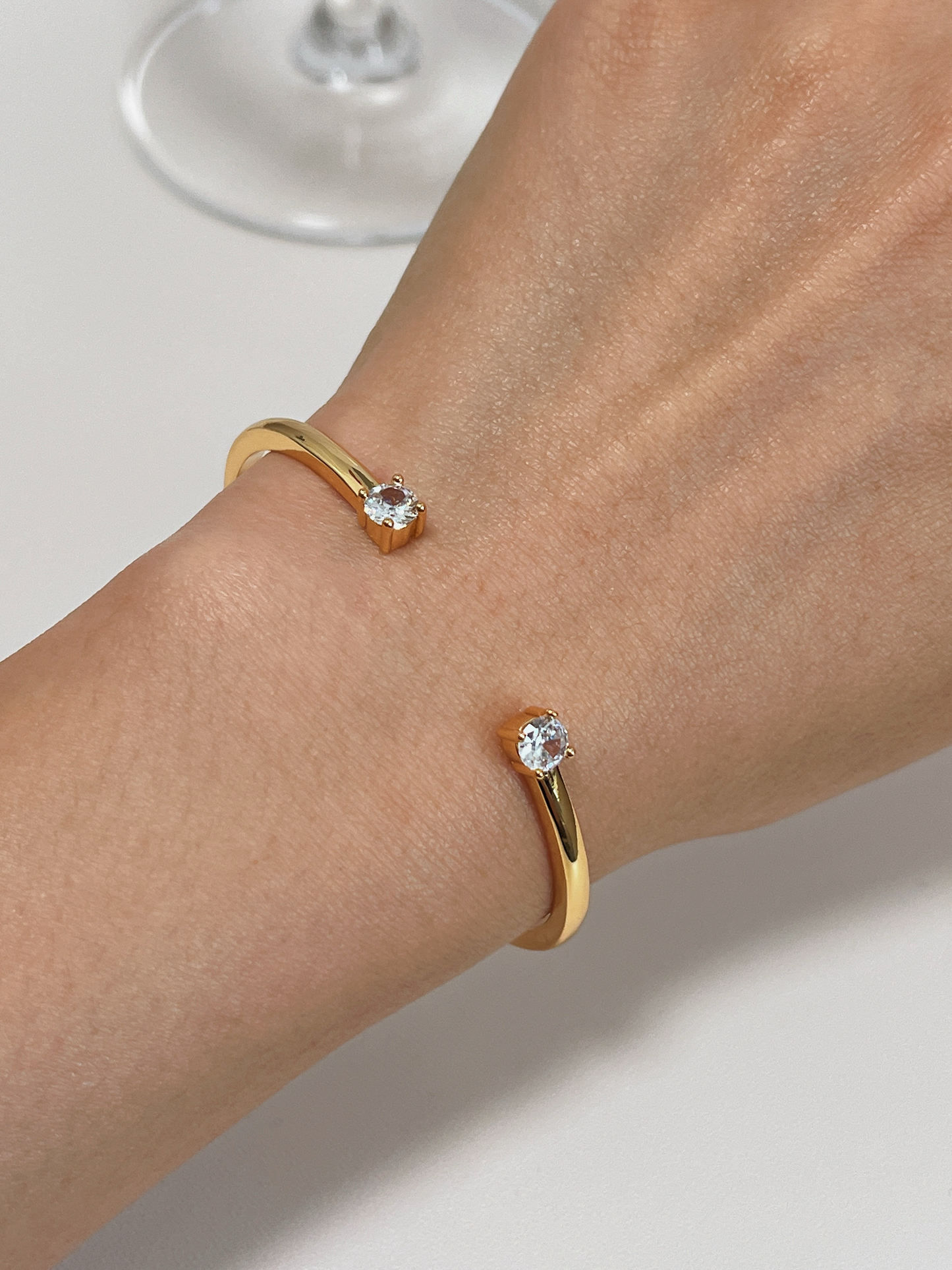 A model styling the Justine gold duo-stone cuff bangle on her wrist, showcasing the open gap design and brilliant solitaire stones.
