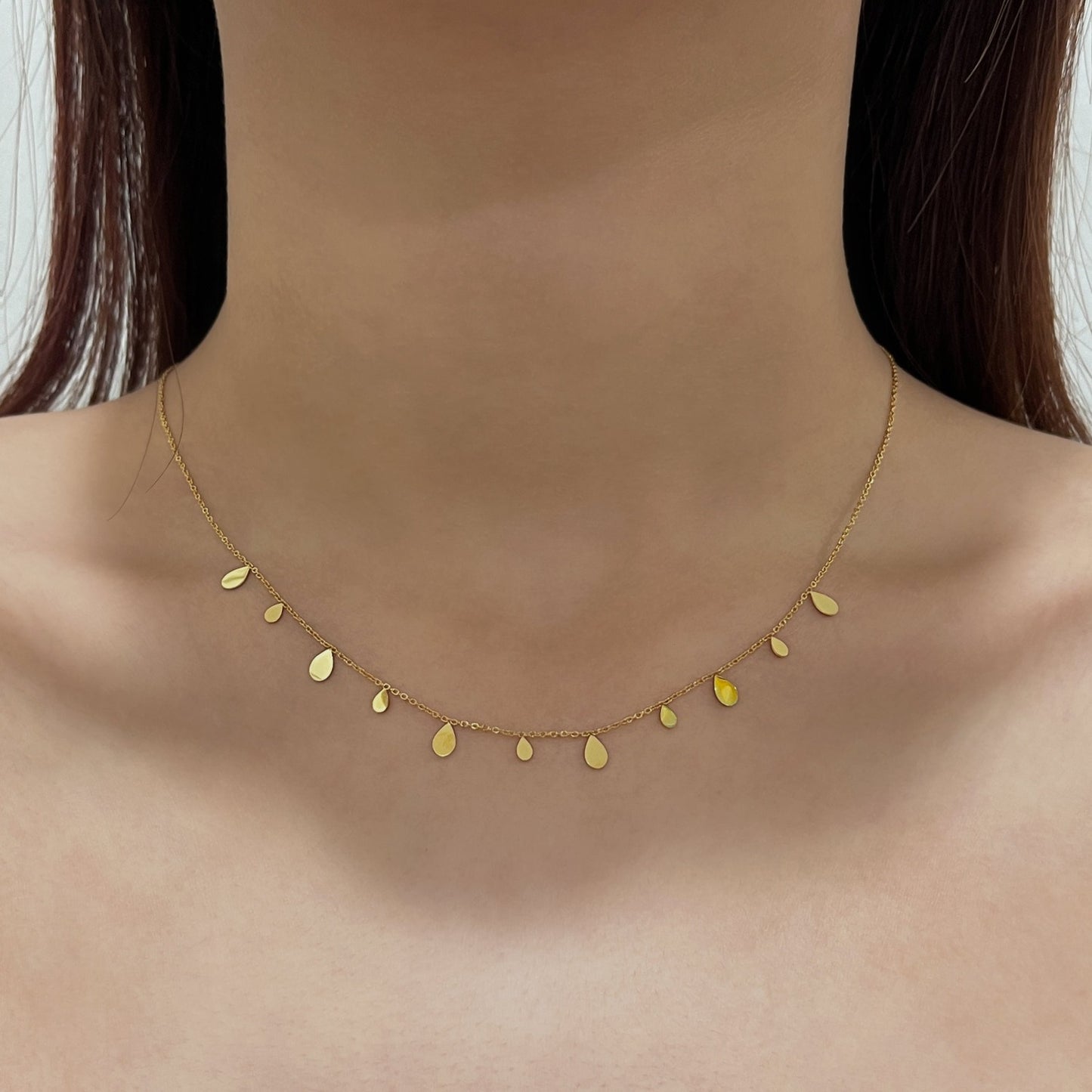 Woman neckline displaying the minimalist look of a molten gold teardrop charm close up