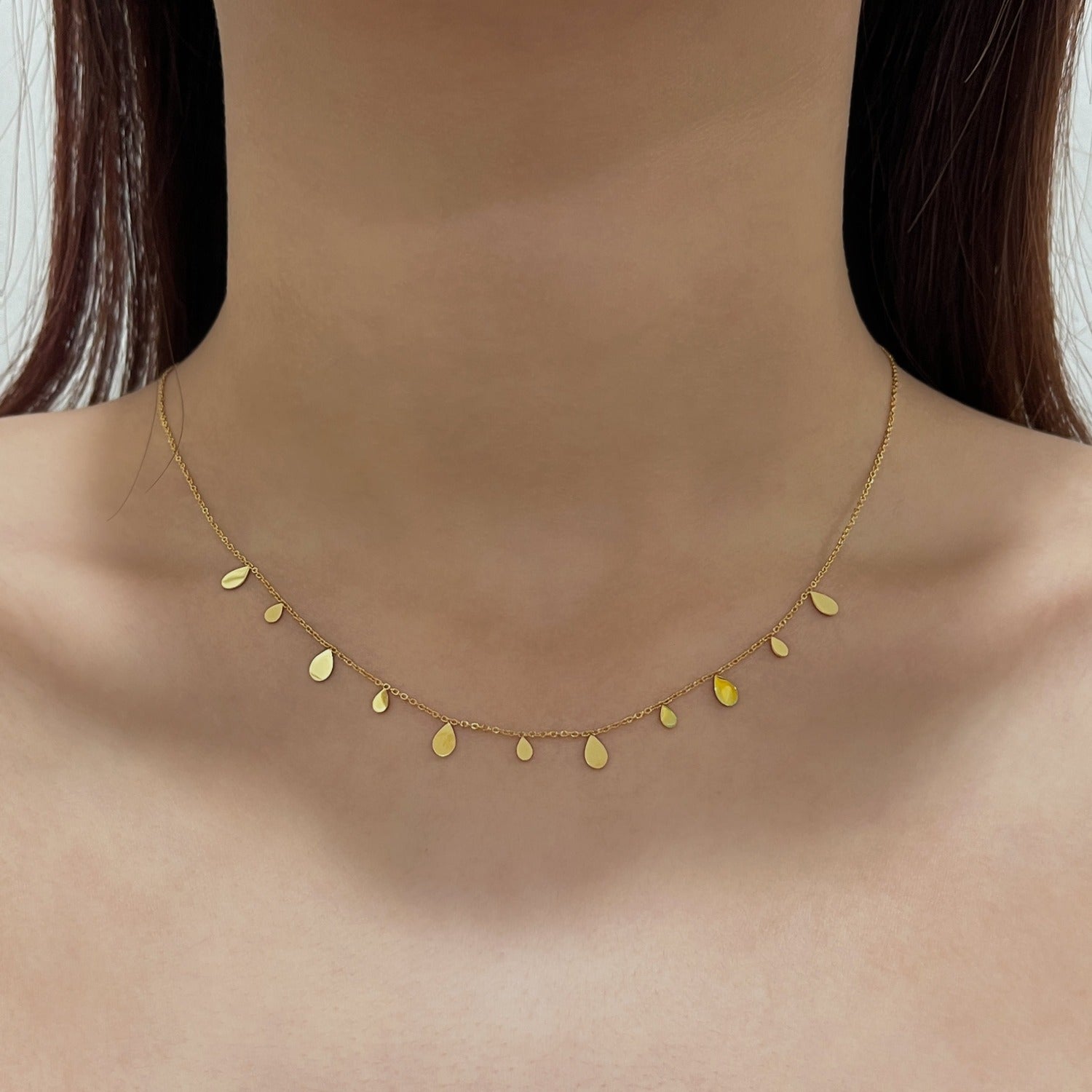 Woman neckline displaying the minimalist look of a molten gold teardrop charm close up