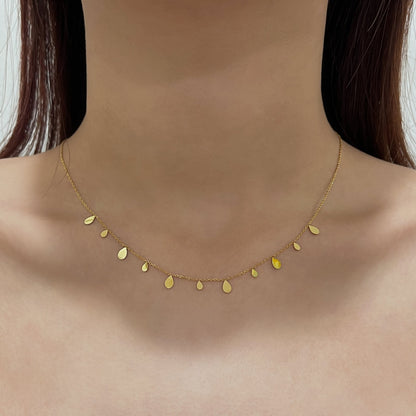 Woman neckline displaying the minimalist look of a molten gold teardrop charm close up