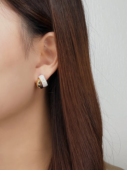 Model side view styling a single piercing gold pearl crossover earring on lobe