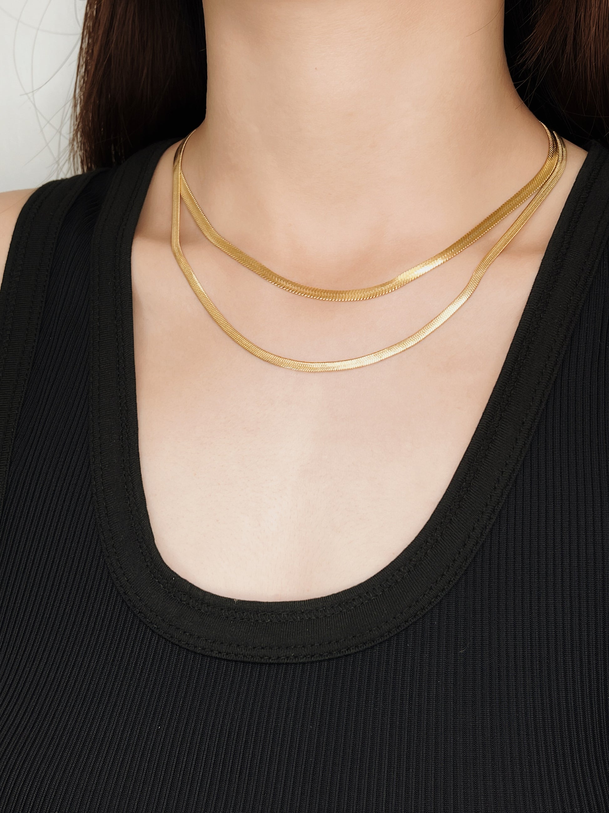 Close up lifestyle portrait of a woman wearing a heavy 5mm and 4mm herringbone gold choker on her collarbone