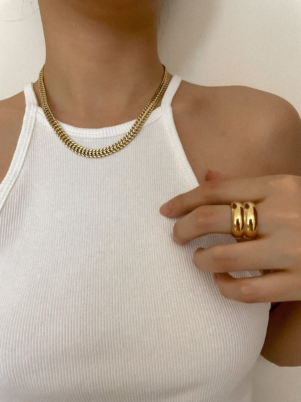 Modern jewelry stack featuring wide gold cigar rings on hand