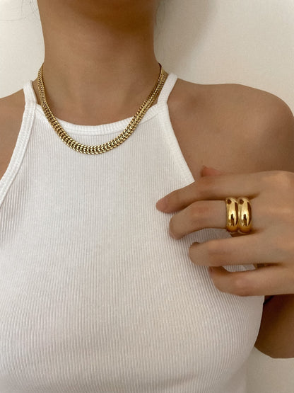 Modern jewelry stack featuring wide gold cigar rings on hand