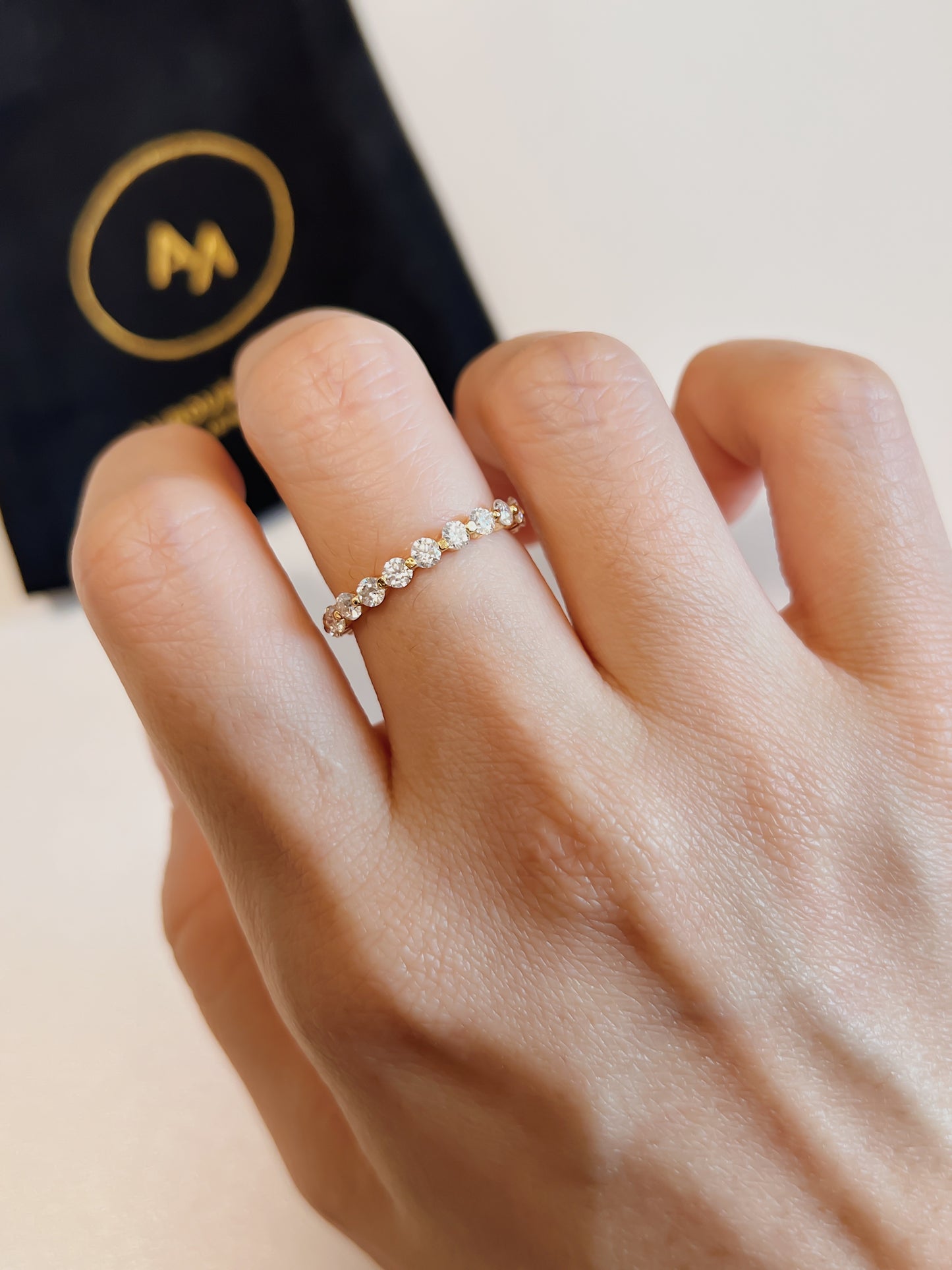 Front lifestyle view of a floating shared prong eternity band styled beautifully on a clean minimal finger