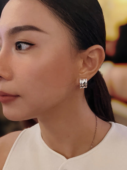 Model wearing silver Molly vintage ribbed clip-on earring styled with a white top and low ponytail