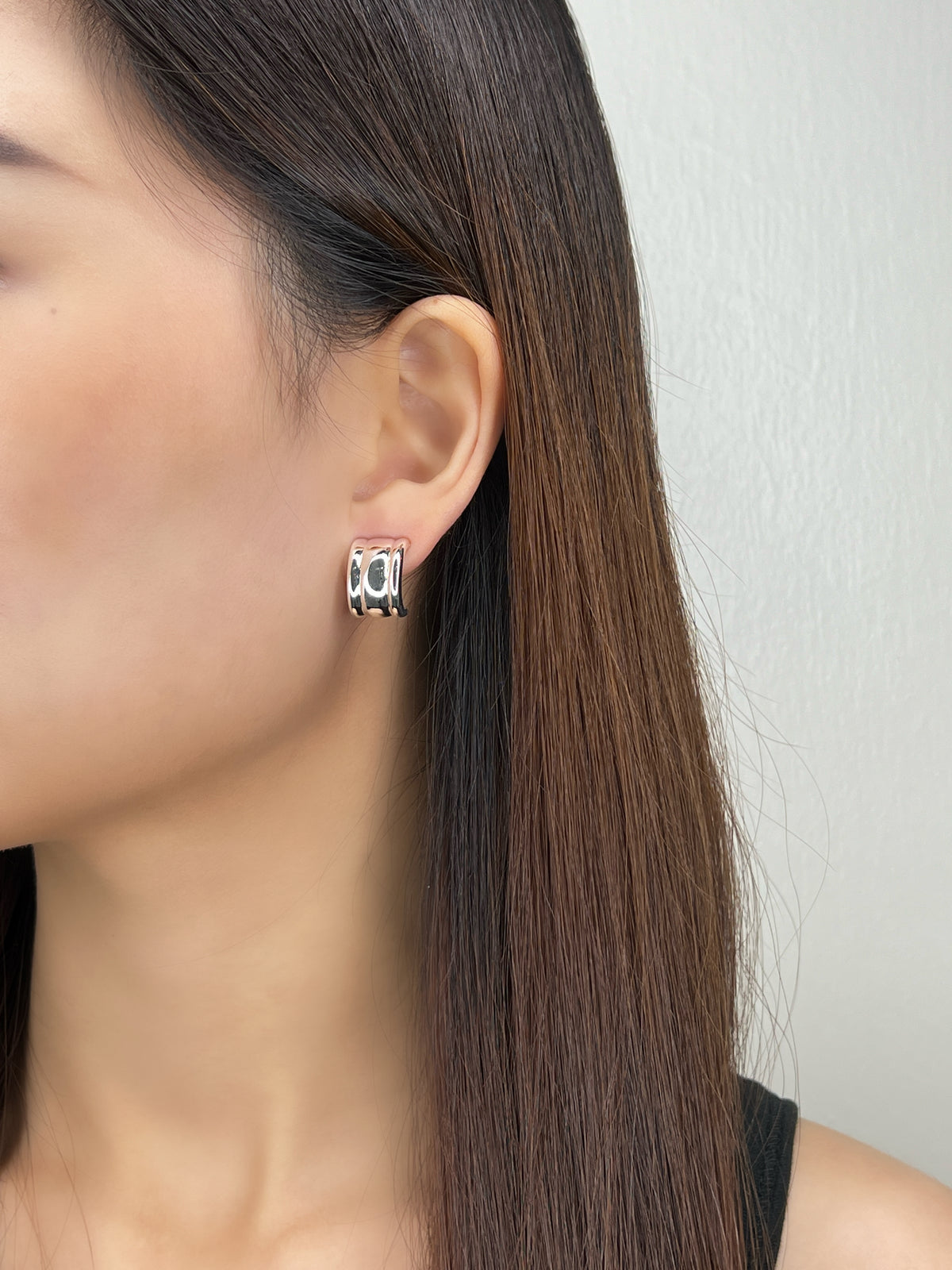 Model wearing silver Molly vintage ribbed clip-on earring on unpierced earlobe, three-quarter view