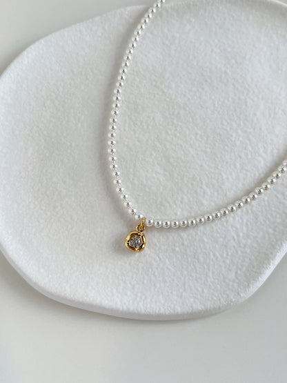 Close-up catalog shot highlighting the natural white luster of a premium dainty pearl chain resting against a neutral stone ledge