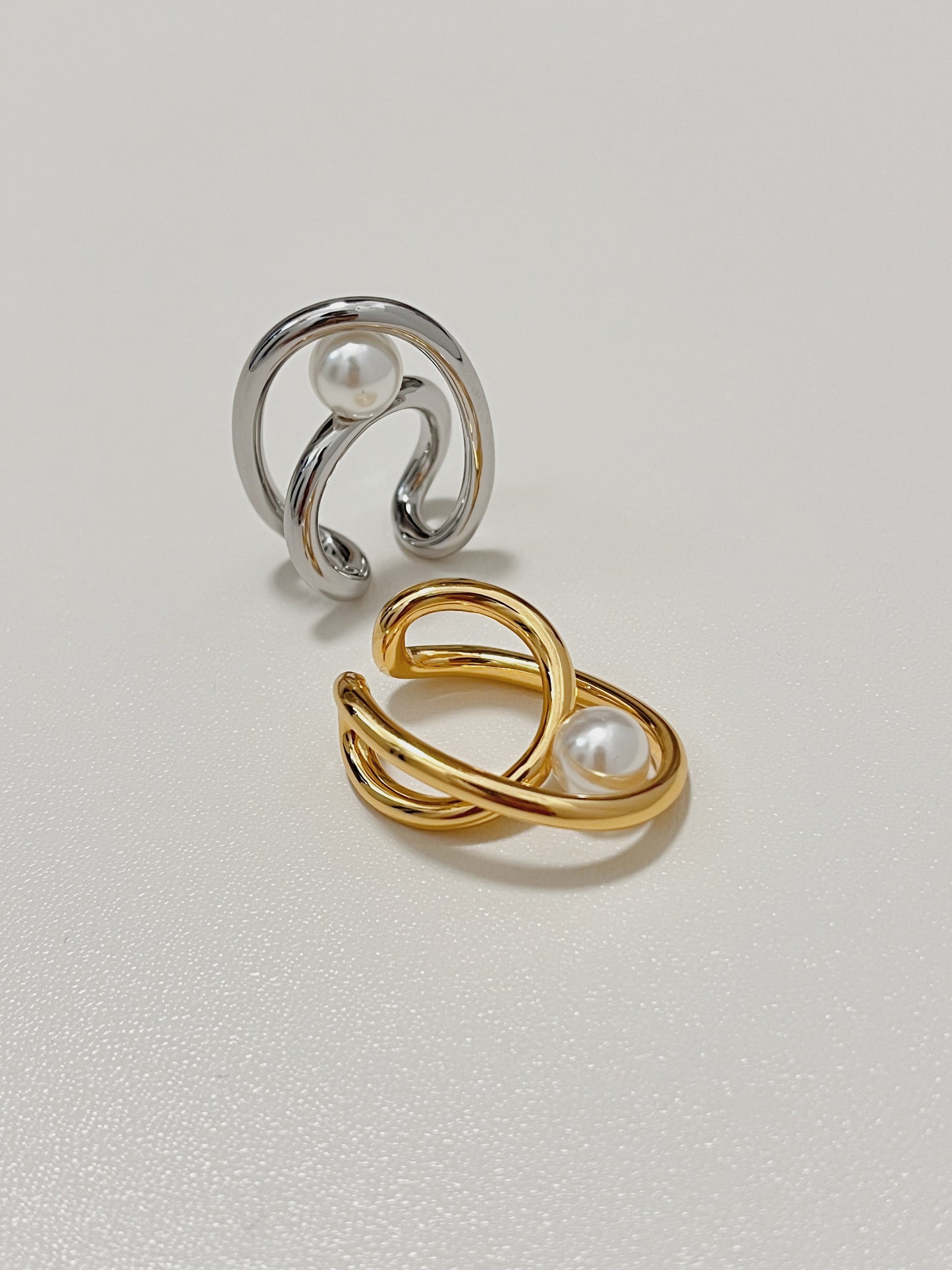 Elevated macro angle of the Karolina non-pierced statement cuffs in polished silver and gold tone, displaying the clean craftsmanship and nested asymmetric wire architecture.